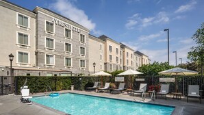 Een hotel met een zwembad, ligbedden en parasols.