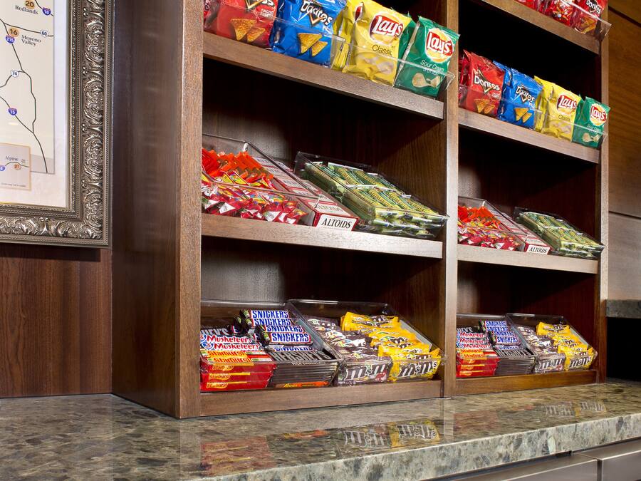 A snack shelf stocked with various chips and a wine cooler with bottles.