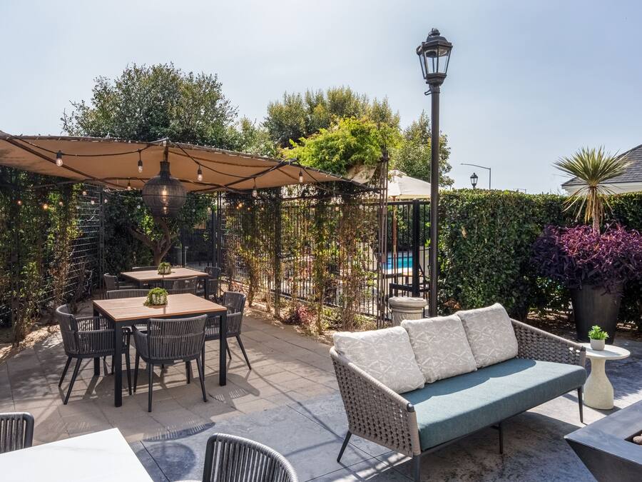An outdoor patio area with a table and chairs, a sofa, and a lamp post.