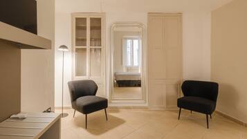 Une pièce avec deux fauteuils noirs, une armoire blanche et un lit à l’arrière-plan.