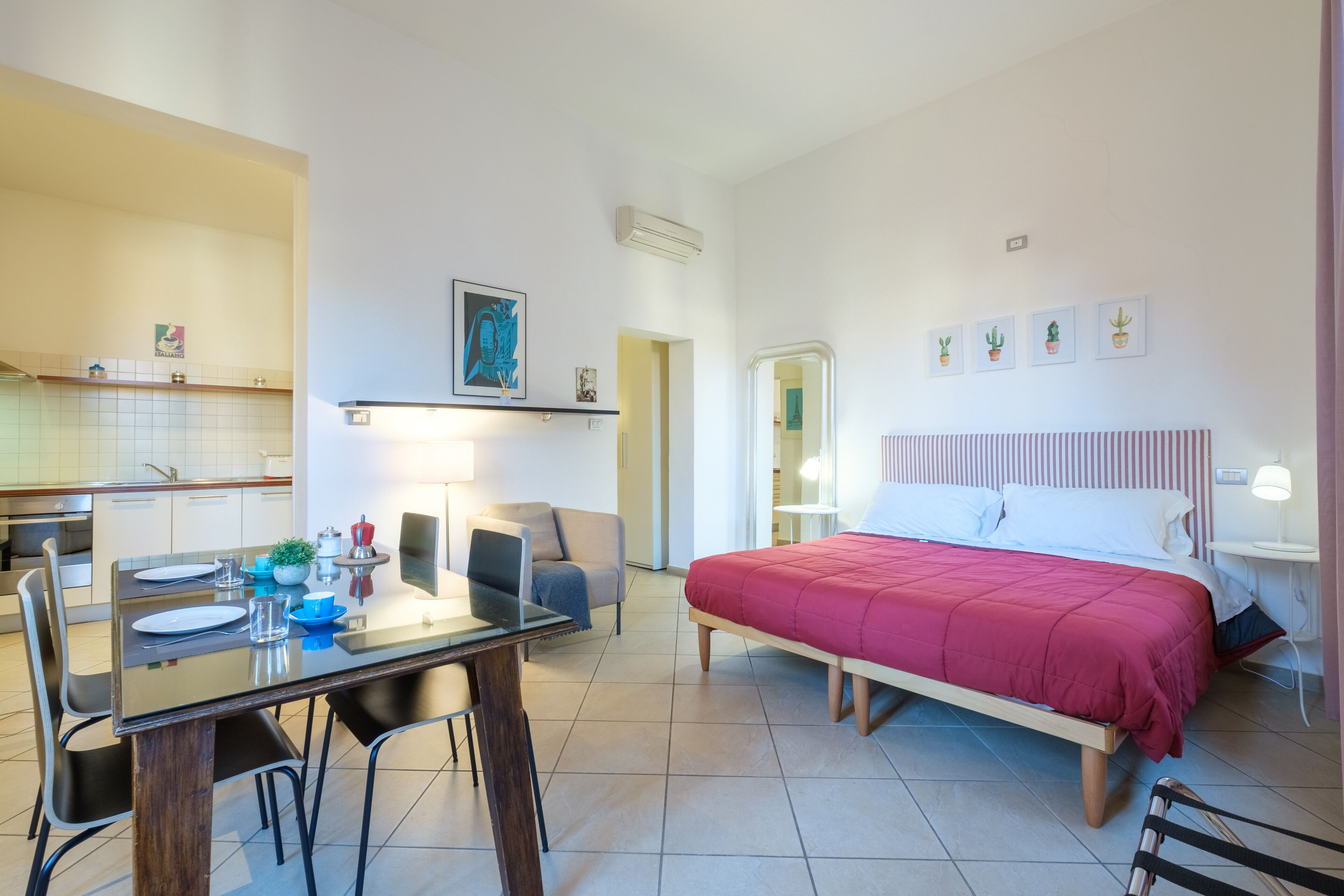 Quarto de hotel moderno com cama, escrivaninha, cadeira, mesa de jantar e cozinha.