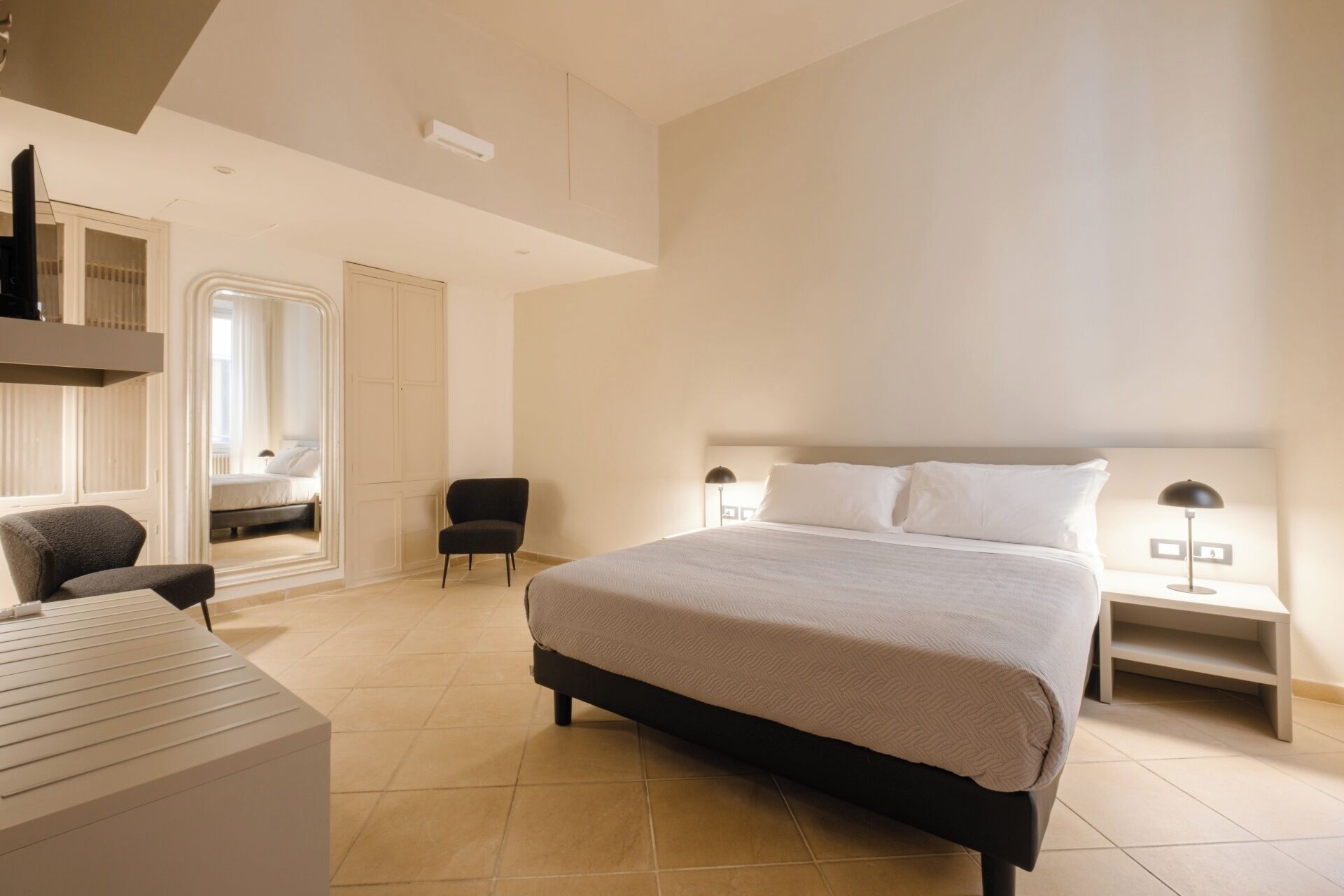 Une chambre d’hôtel moderne équipée d’un grand lit, d’un bureau, d’une chaise et d’une armoire.