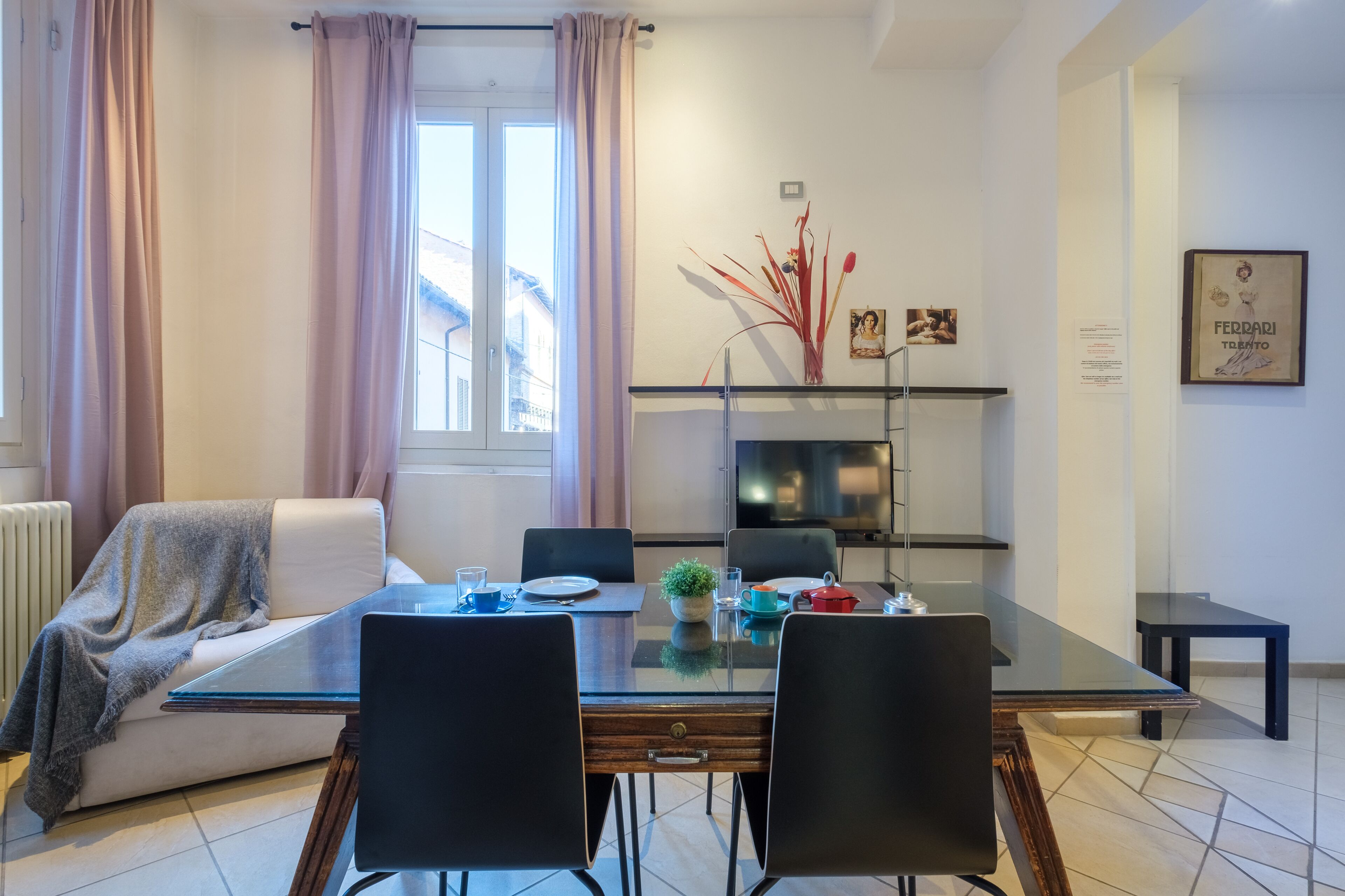 Una sala de estar moderna con una mesa de comedor de vidrio, sillas negras, un sofá blanco y una chimenea.