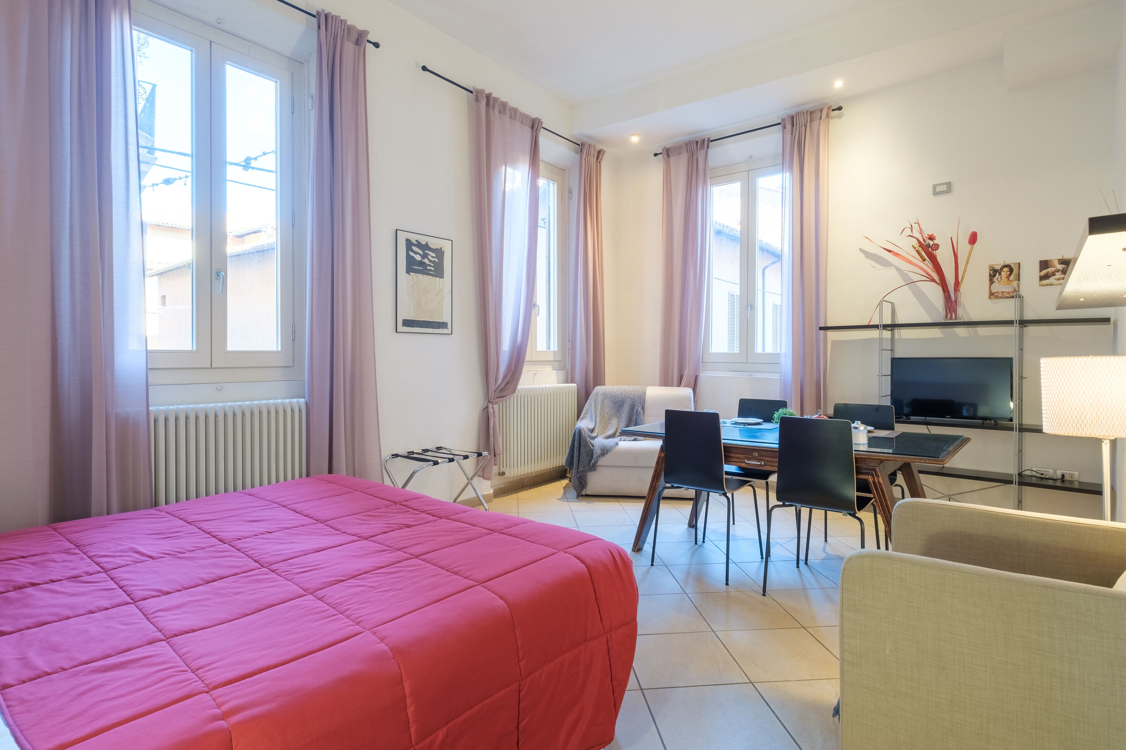 Habitación de hotel con una cama grande, un escritorio con silla, televisión y zona de comedor.