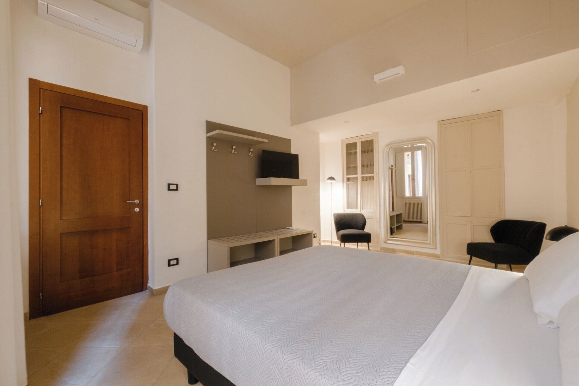 Une chambre à coucher avec un lit, une armoire, une chaise et un miroir.