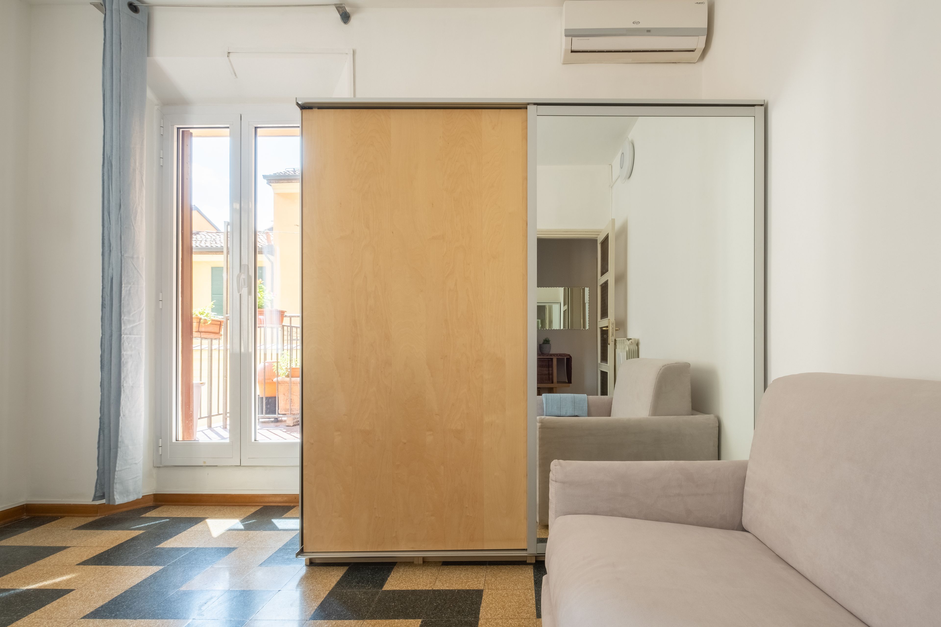 A modern room with a sofa, a sliding door, and a view of the outside.