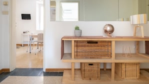 Un baño moderno con un espejo grande, un tocador de madera, cestas de mimbre, un globo y una lámpara a rayas.