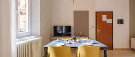 A dining area with a table set for four, a television, and a door with a notice.