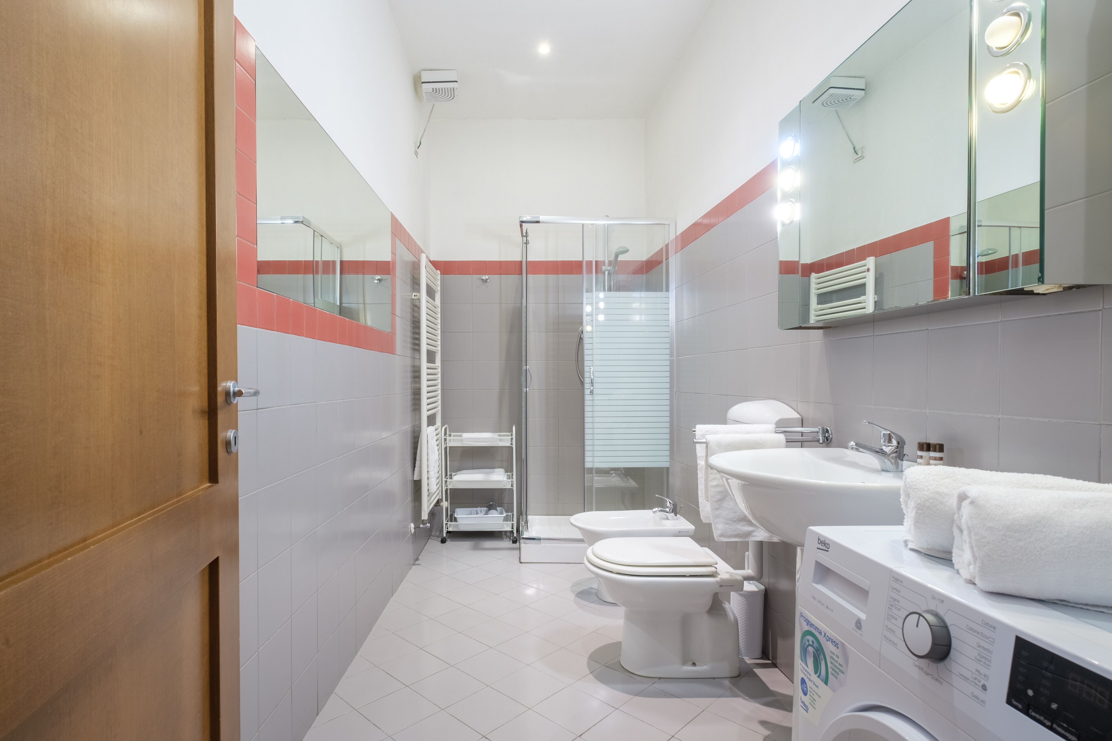 Ein modernes Badezimmer mit Duschkabine aus Glas, Toilette, Bidet und Waschmaschine.