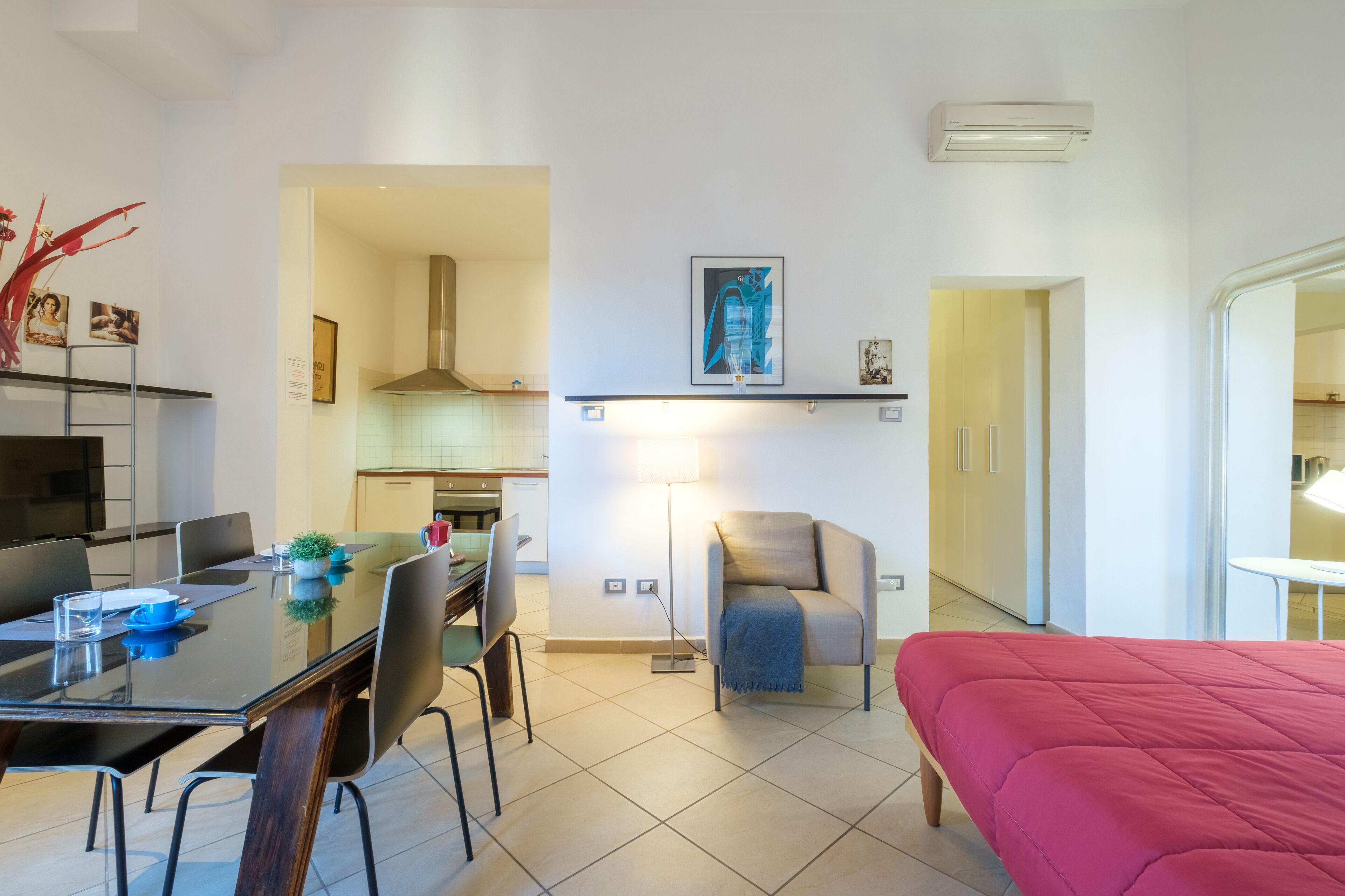 A modern hotel room with a dining area, kitchenette, and a bed.