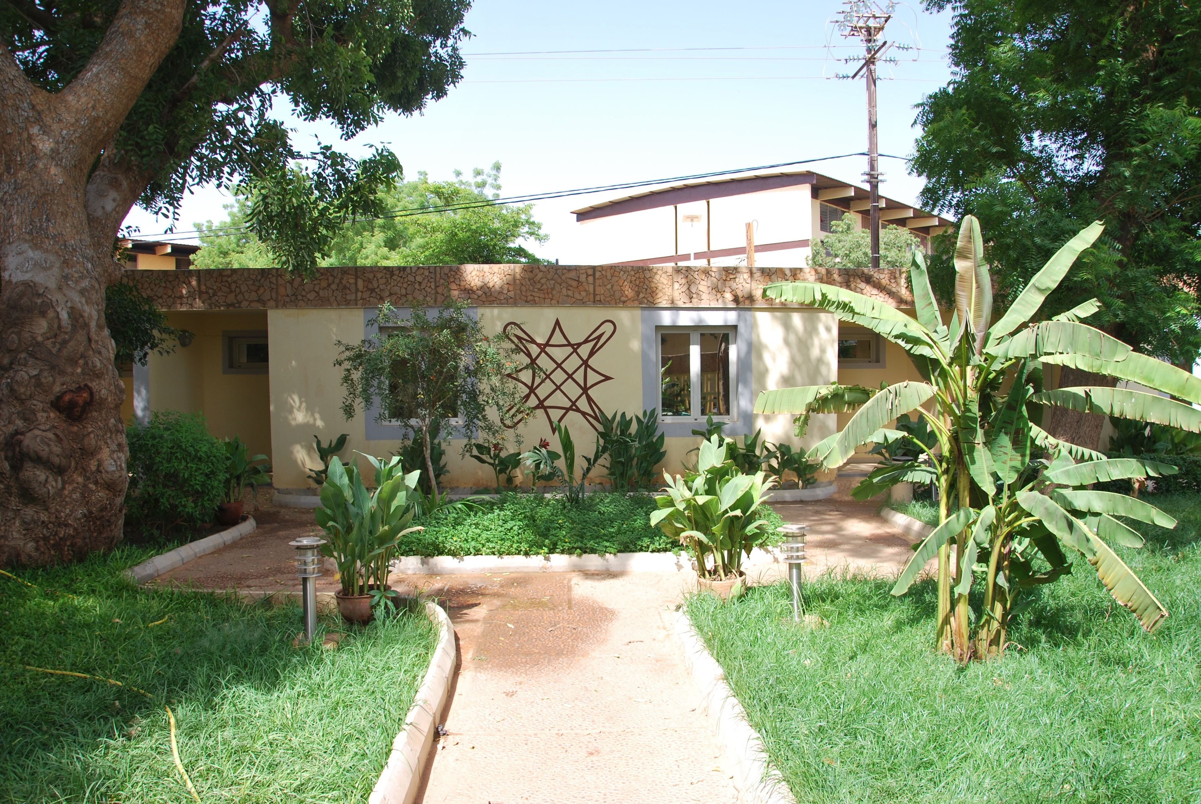 Uma casa com fachada de pedra, entrada com calçada e jardim com diversas plantas.