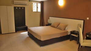 Une chambre à coucher comprenant un lit, un bureau, une chaise, une armoire et un appareil de climatisation.