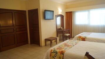 A hotel room with two beds, a television, a desk, and a mirror.