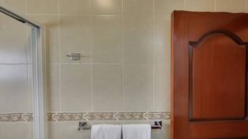 Un baño con ducha, puerta de madera y toallero.