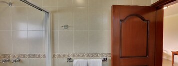 Un baño con ducha, puerta de madera y toallero.