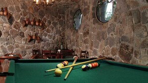 A pool table with billiard balls and cues, surrounded by stone walls and wooden furniture. - Hotel Argento (Cuernavaca)