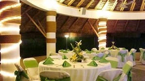 A round table with white tablecloths and green sashes, surrounded by chairs with green sashes. - Hotel Argento (Cuernavaca)