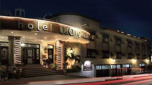 A hotel with a curved facade, illuminated signage, and a well-lit entrance. - Hotel Argento (Cuernavaca)