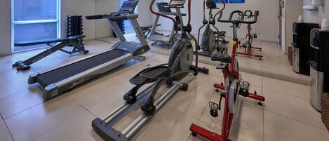 Un gimnasio con cintas de correr, elípticas y bicicletas estáticas.