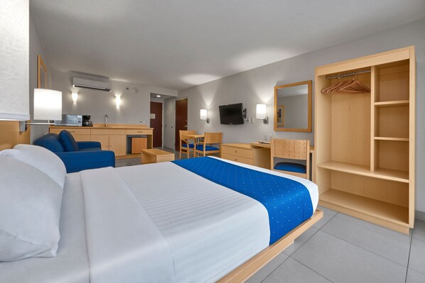 Una habitación de hotel con una cama grande, un escritorio, una silla, un armario y un televisor.