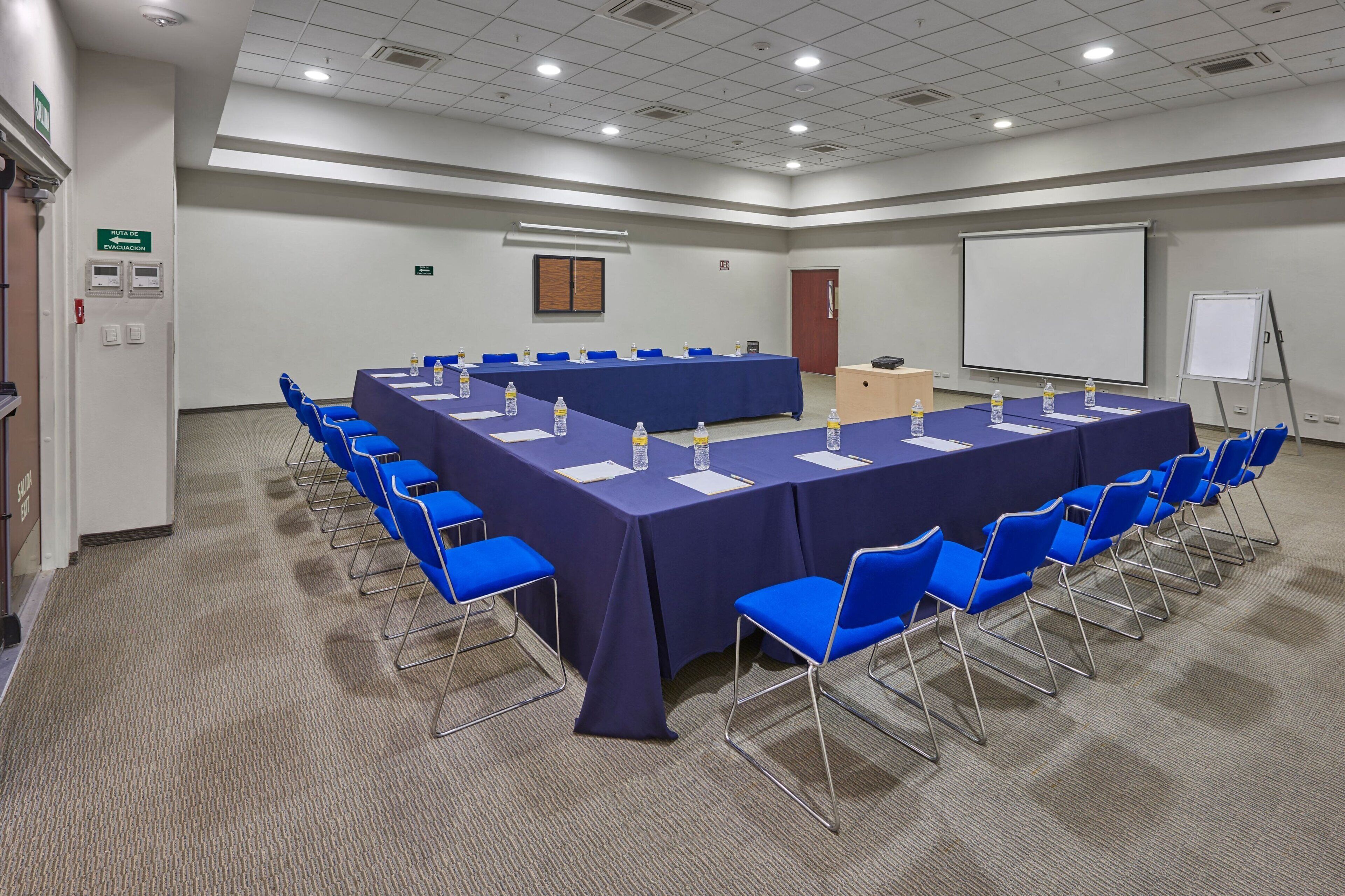 A conference room with a long table, blue chairs, and a whiteboard.