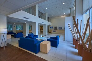 A spacious lobby with blue seating, a reception desk, and a view of the city. - City Express by Marriott Xalapa (Xalapa)