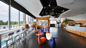 Rebedor modern d'hotel amb zona de bar, seients i taulell de recepció.