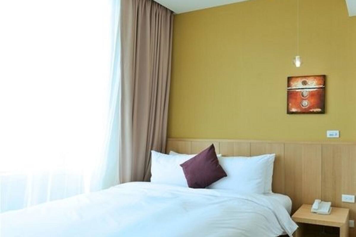 Habitación de hotel con cama, mesita de noche, teléfono y un cuadro en la pared.