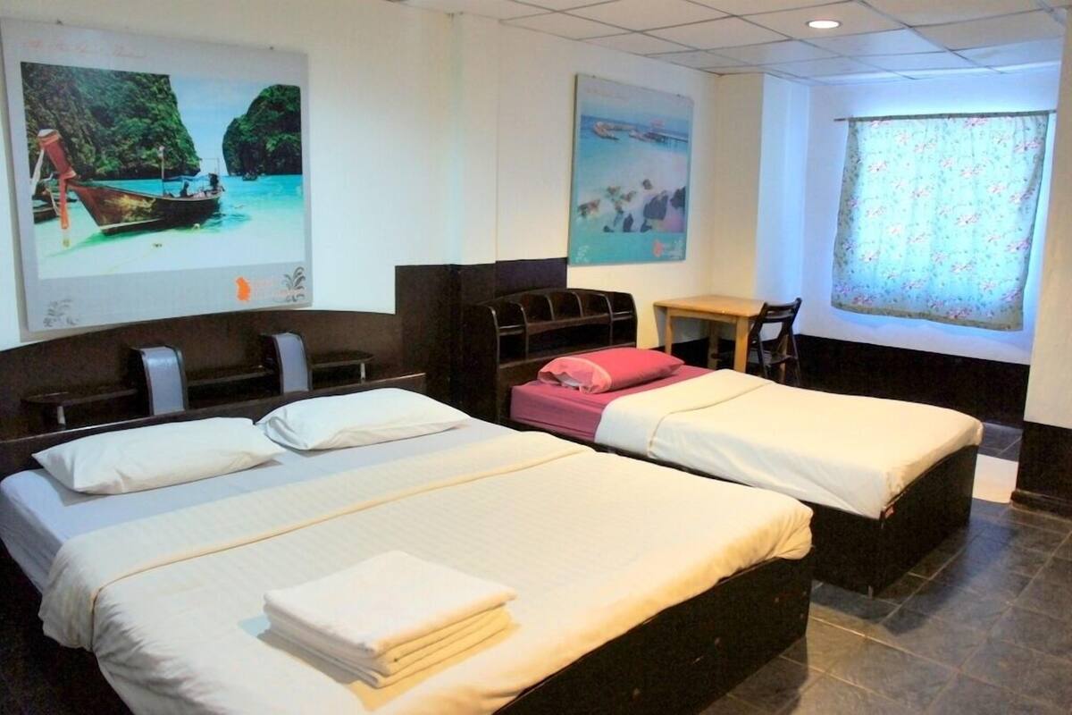 A hotel room with two beds, a desk, and a window with curtains.