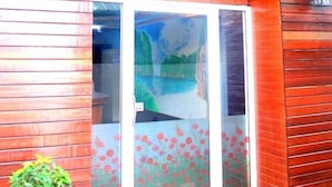 Un edificio de madera con puerta corredera de vidrio y una pequeña planta en maceta.