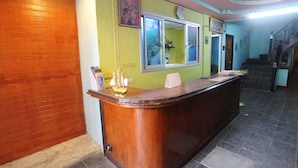 Una recepción con detalles de madera, un reloj encima y una ventana que da a zonas verdes.