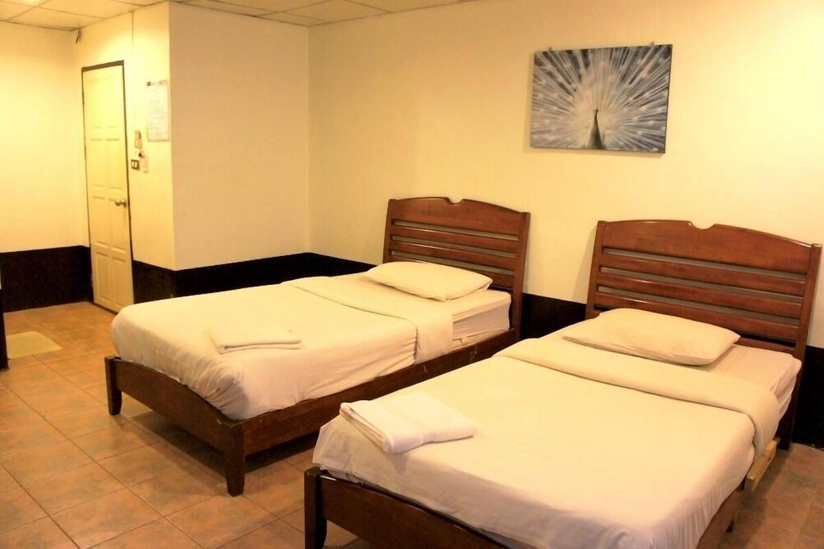 Two single beds with wooden frames and white bedding, a door, and a wall-mounted abstract art piece.