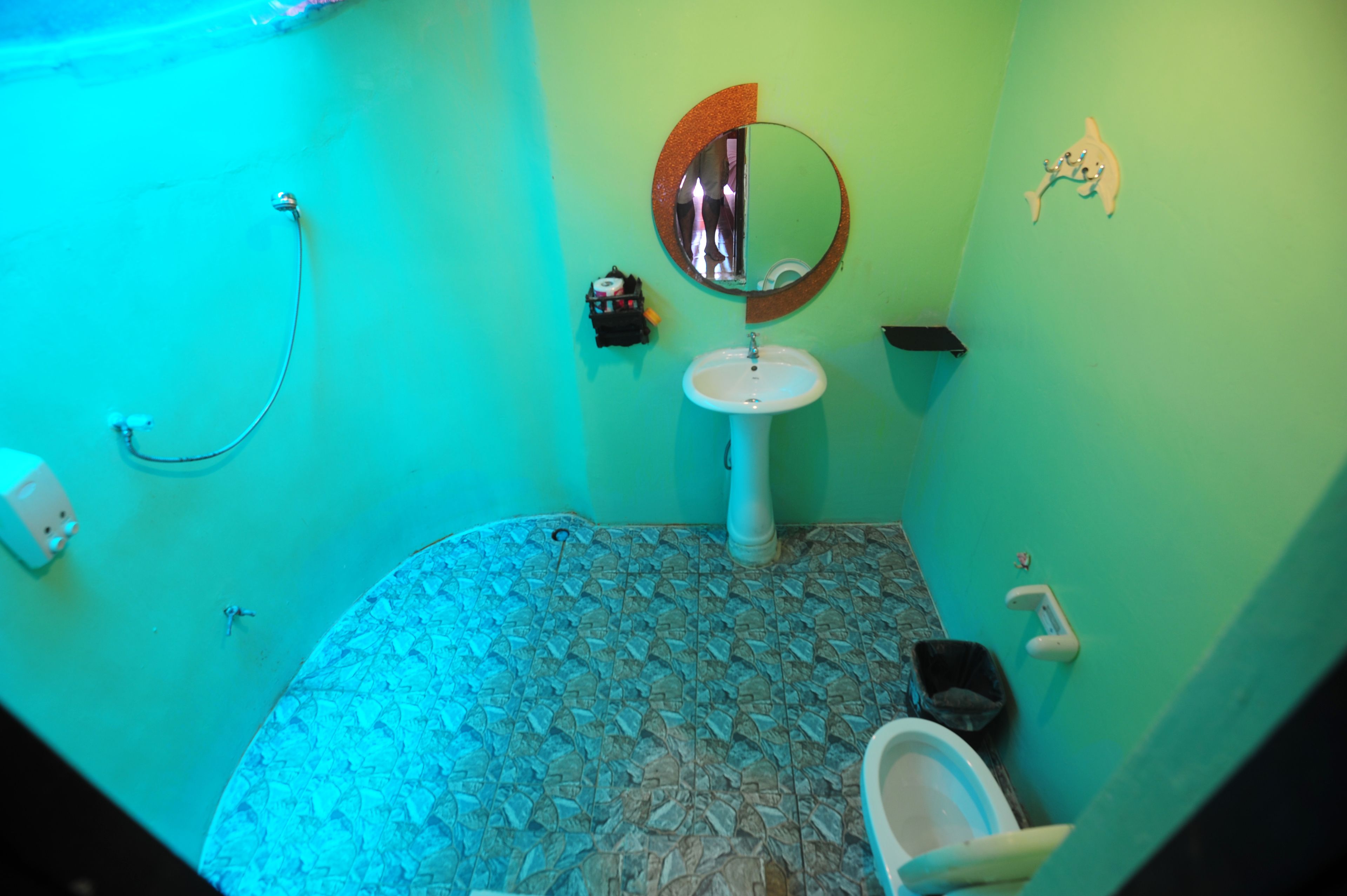 A bathroom with a round mirror, a sink, and a toilet.