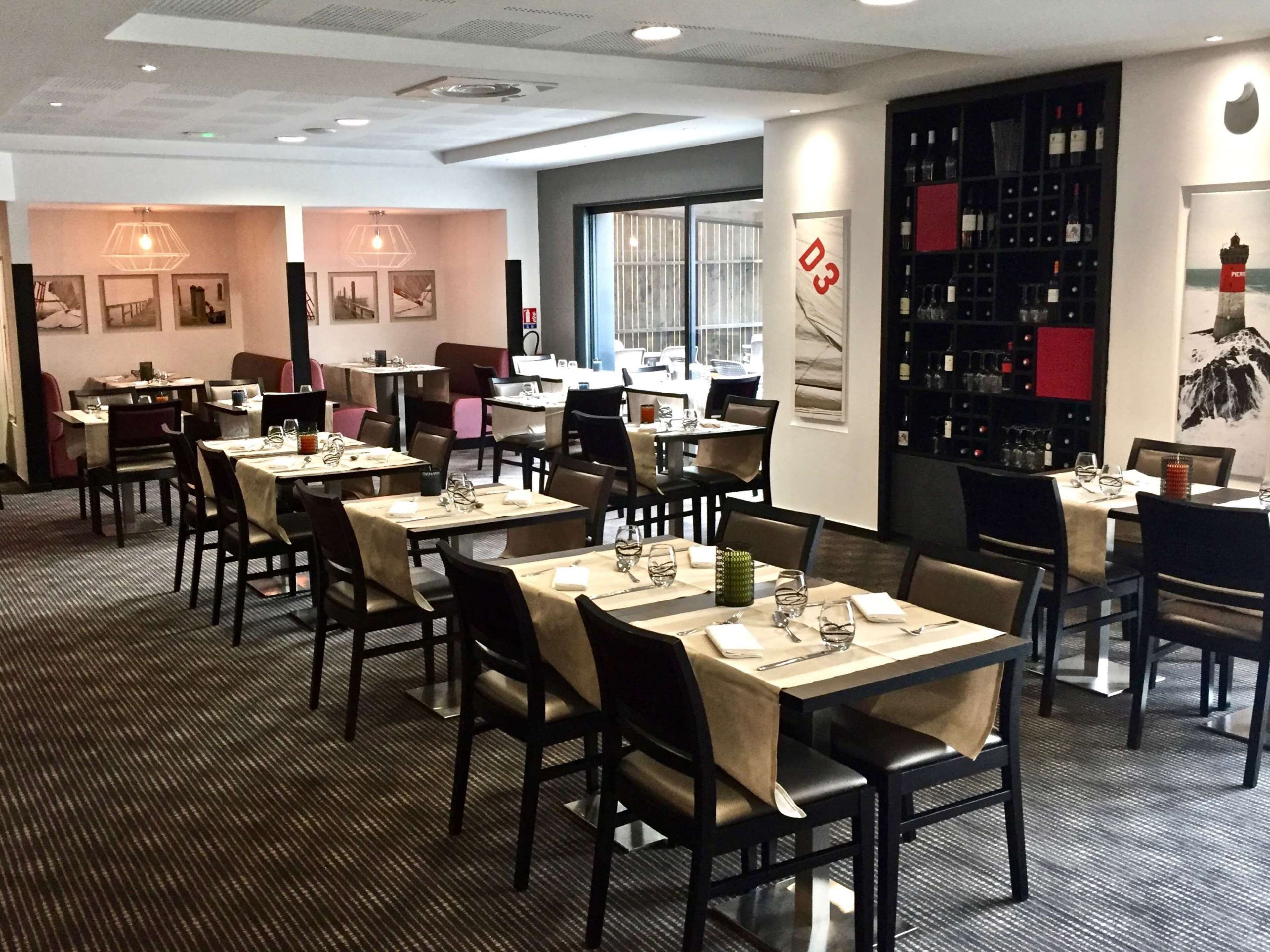 A restaurant with multiple tables and chairs, a wine rack, and framed pictures on the walls.