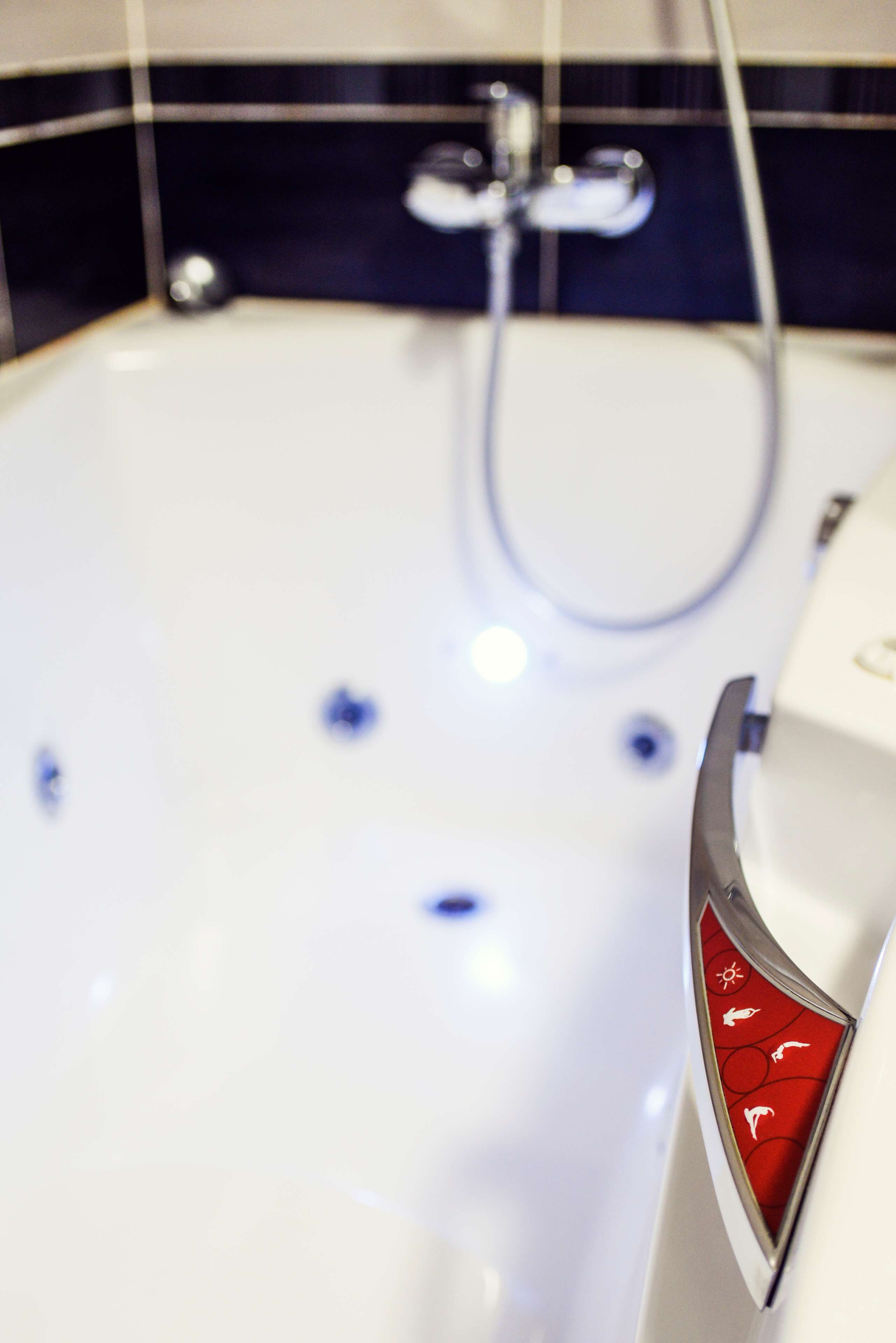 Un baño con un lavabo blanco, un panel de control rojo y un grifo cromado.