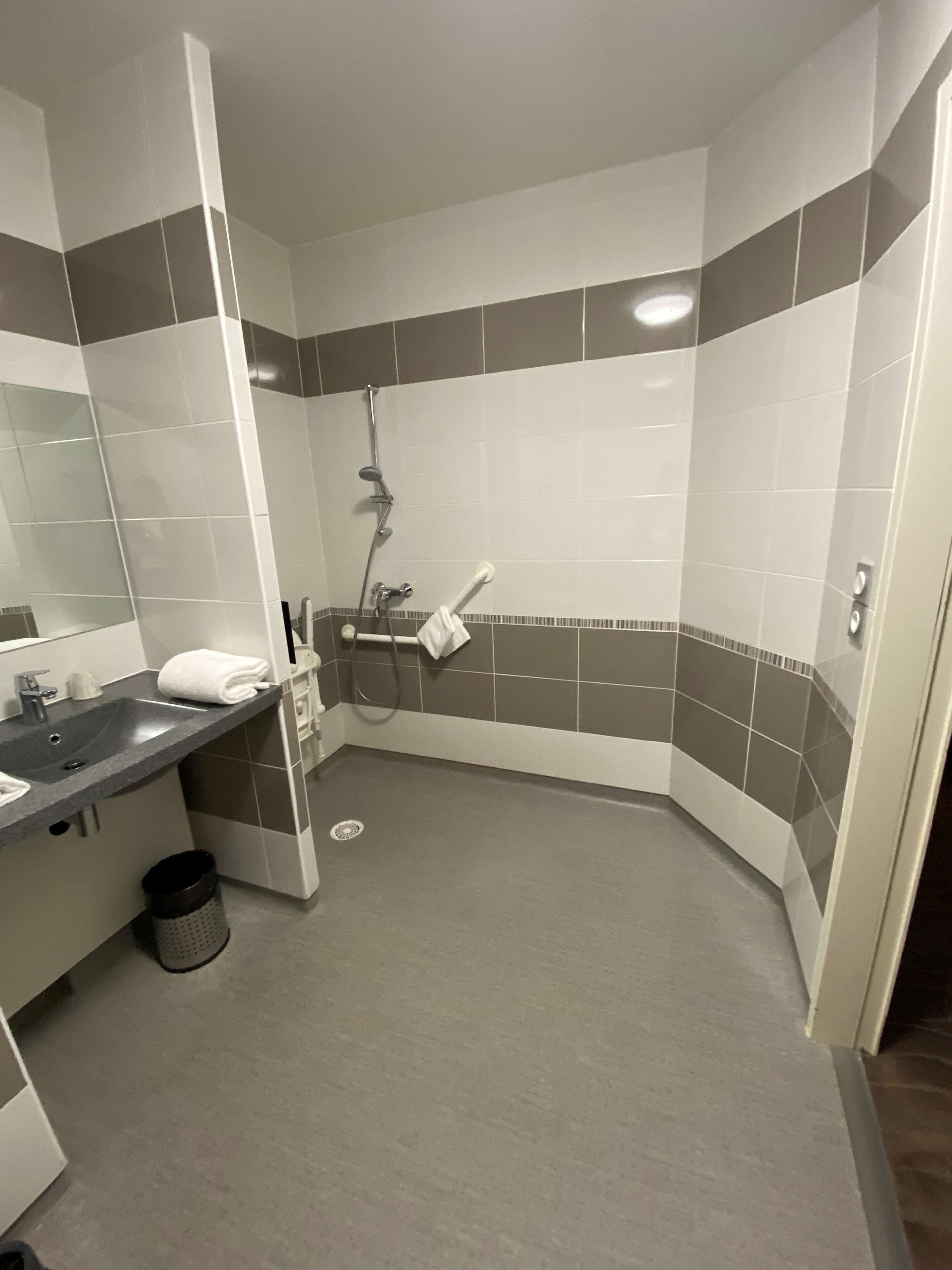 Uma casa de banho moderna com chuveiro de canto, lavatório com espelho e porta-toalhas.