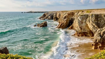 Un paisaje costero con acantilados rocosos y olas rompiendo en la orilla.