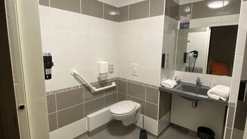 Une salle de bain moderne équipée de toilettes, d’un lavabo et d’un sèche-mains.