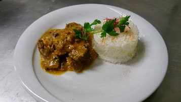 A plate with a meat dish and white rice, garnished with parsley.