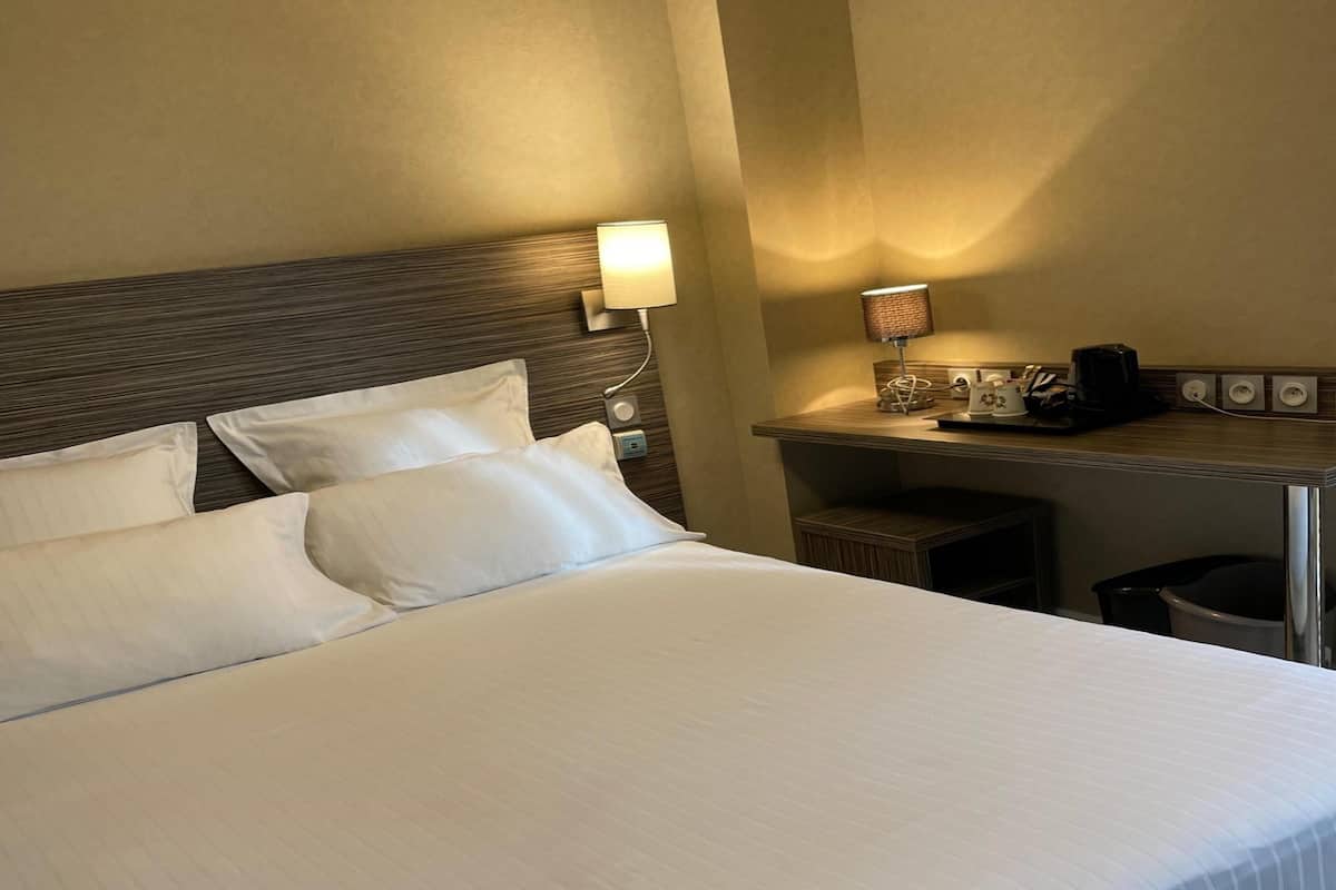 Ein ordentlich bezogenes Bett mit weißen Laken in einem Hotelzimmer.