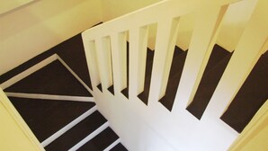 Una escalera blanca con peldaños negros y barandillas blancas.