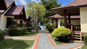 A row of bungalow-style buildings with tiled roofs, a paved pathway, and lush greenery. - Phi Phi Villa Resort (Ko Phi Phi)