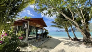 A beachside building with a sign for Thai massage, surrounded by palm trees and a view of the ocean. - Phi Phi Villa Resort (Ko Phi Phi)