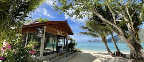 A beachside building with a sign for Thai massage, surrounded by palm trees and a view of the ocean.
