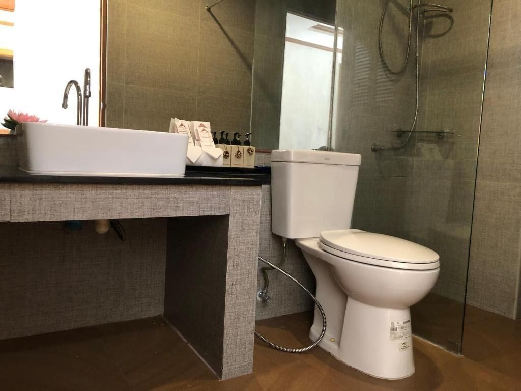 A modern bathroom with a white sink, toilet, and glass shower enclosure.