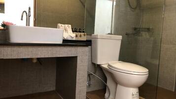 A modern bathroom with a white sink, toilet, and glass shower enclosure.