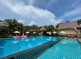 Una piscina al aire libre, sombrillas, sillones reclinables de piscina