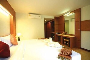 A hotel room with a bed, a nightstand, a lamp, a mirror, and a wooden wardrobe.