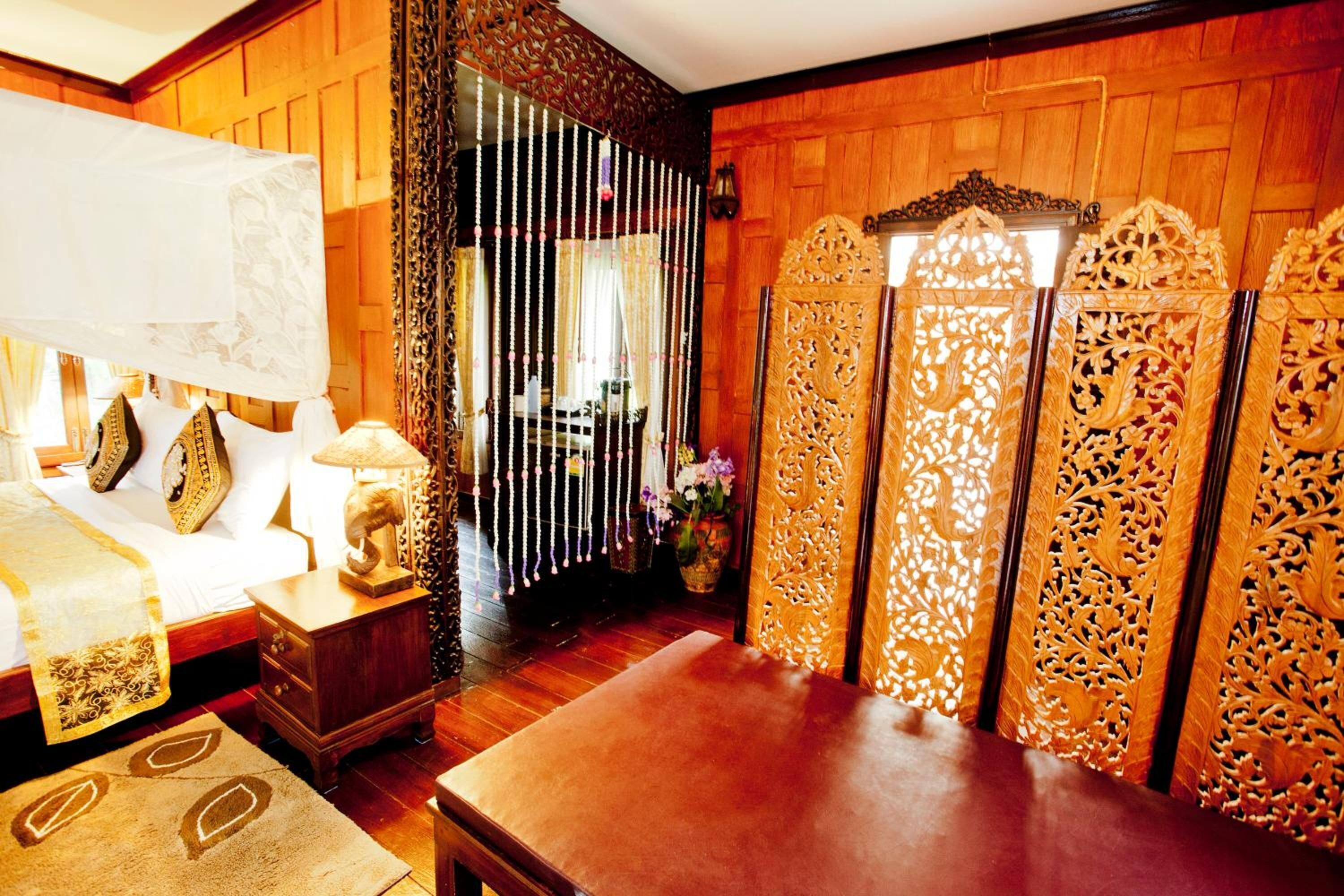 Una habitación tradicional con cama, mesita de noche y un panel de madera con elaborados grabados.