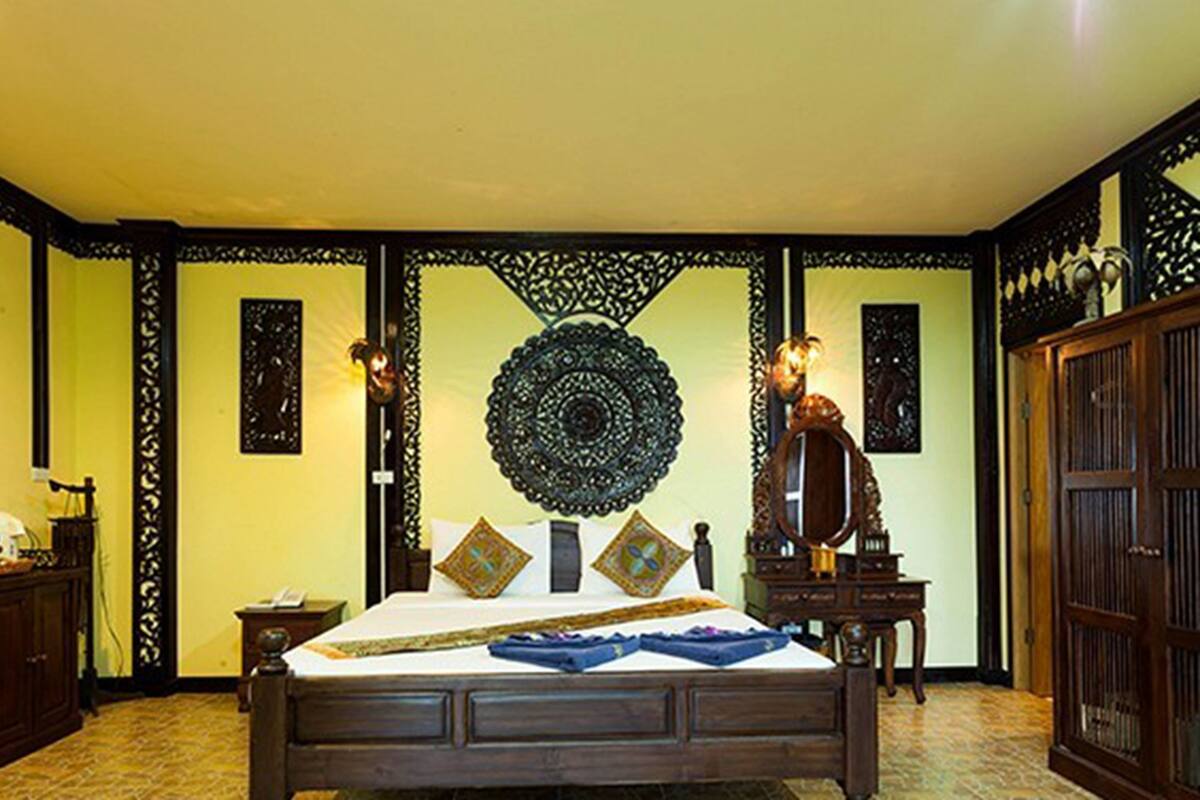 Habitación tradicional con cama, escritorio y paneles decorativos en la pared.